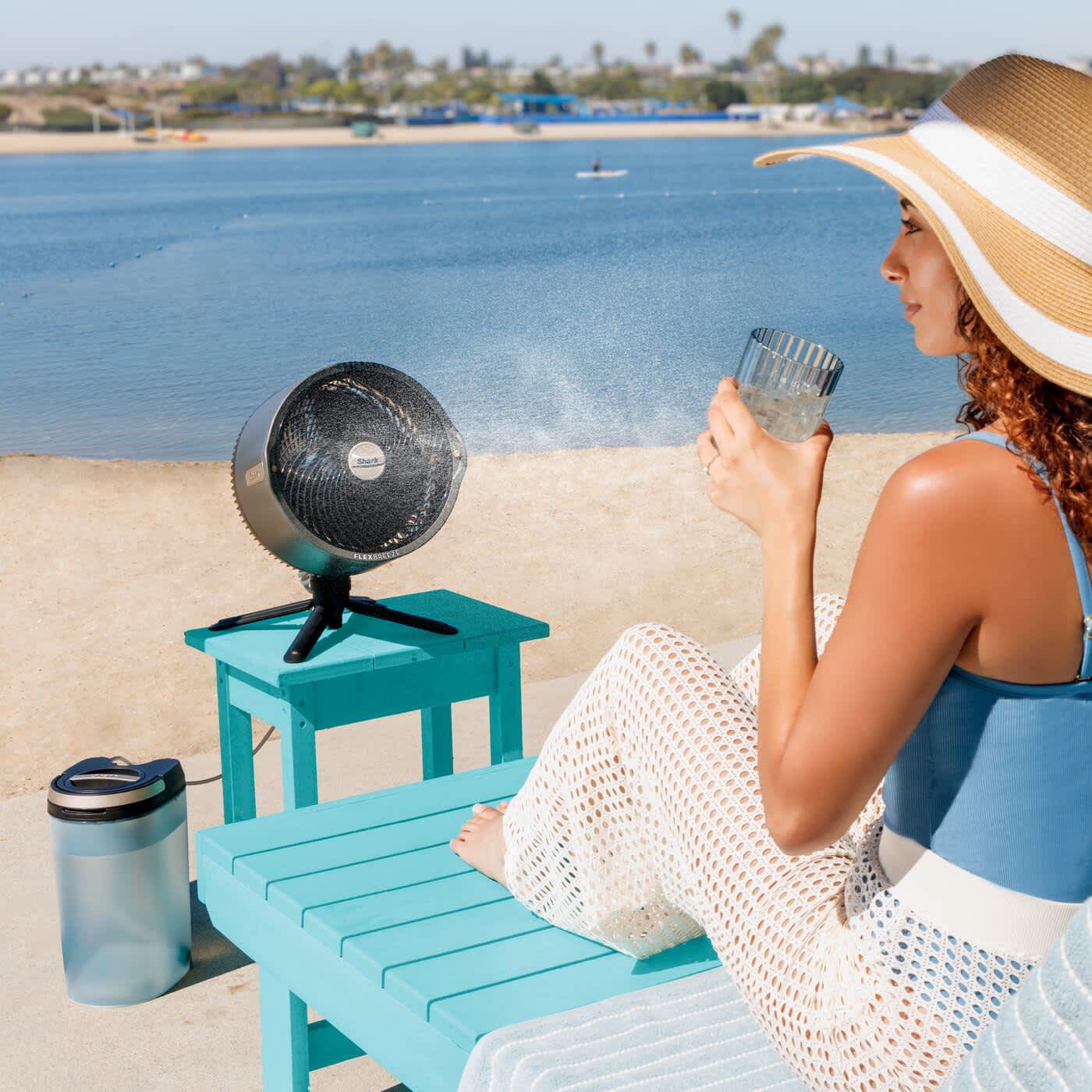 Femme utilisant un ventilateur Shark avec fonction brumisation sur la plage.
