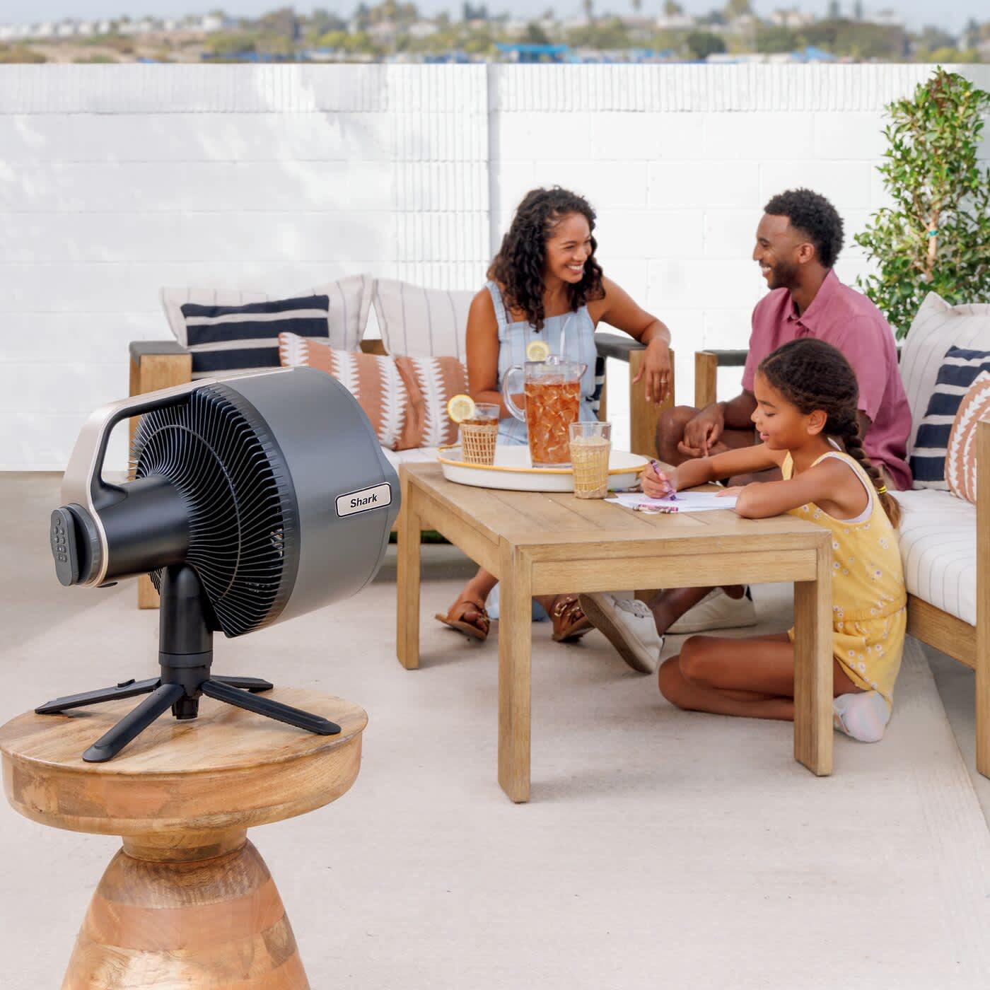 Famille assise autour d&rsquo;une table, utilisant un ventilateur Shark.