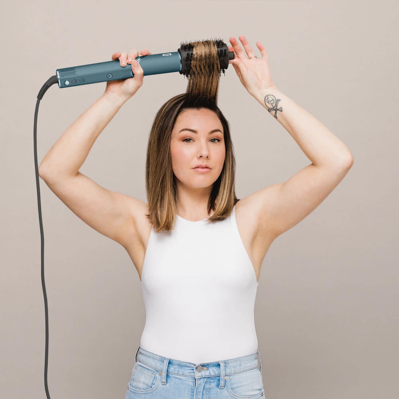 Kobieta nawija swoje brązowe włosy na okrągłą szczotkę suszarko-lok&oacute;wki Shark FlexStyle Styler HD456 w kolorze morskim