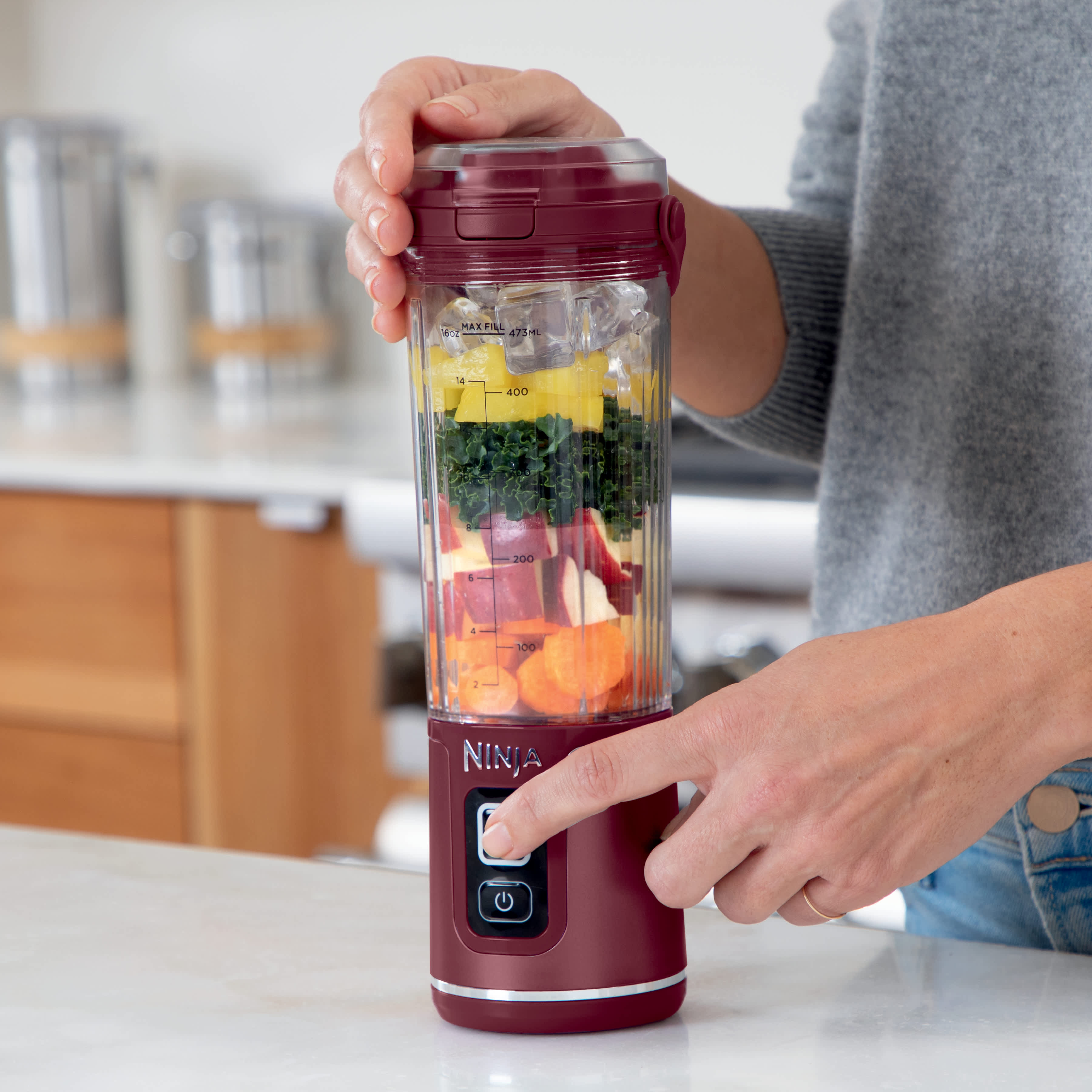 Personne mixant des fruits dans le blender portable Ninja.