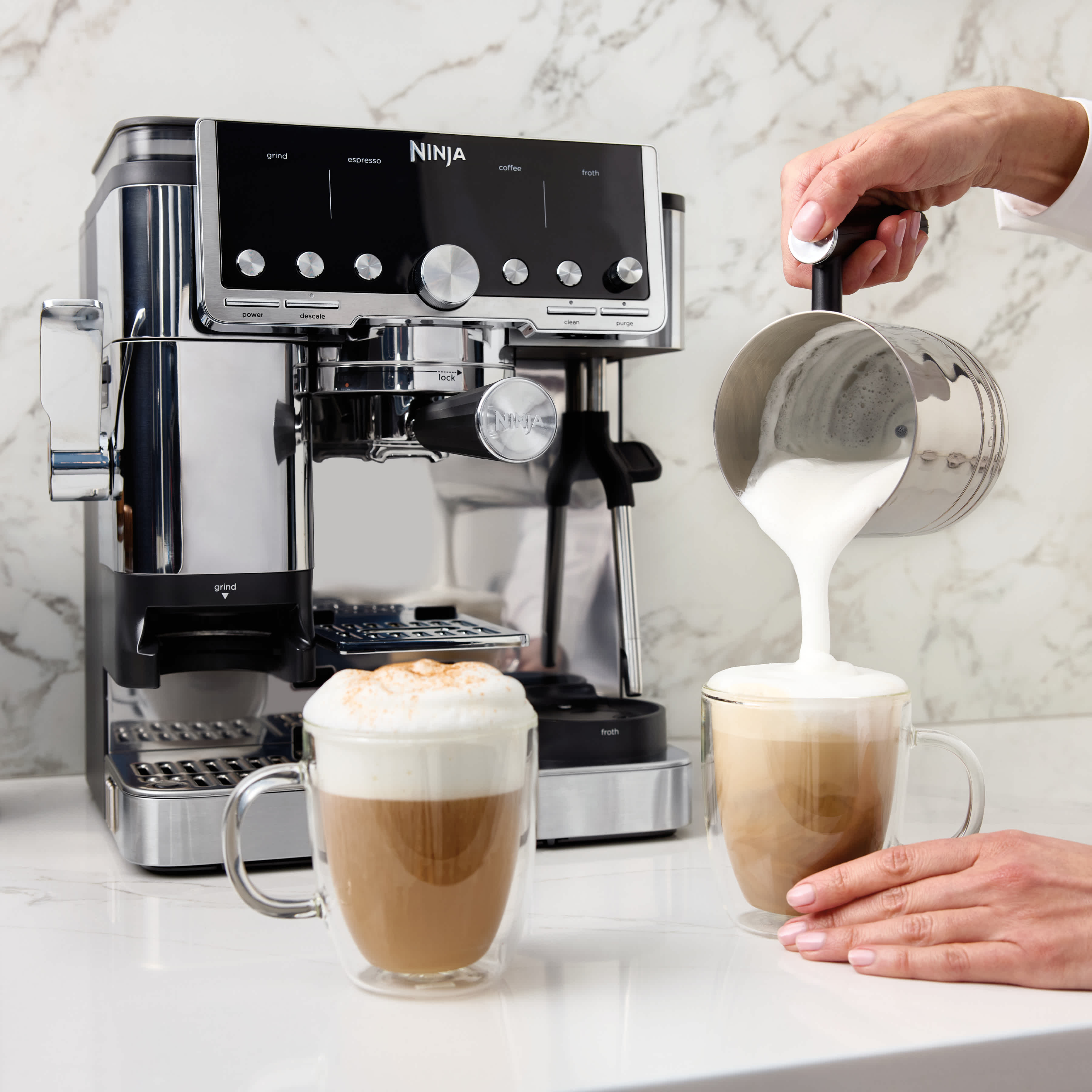 Personne versant du lait mousseux dans un caf&eacute;.