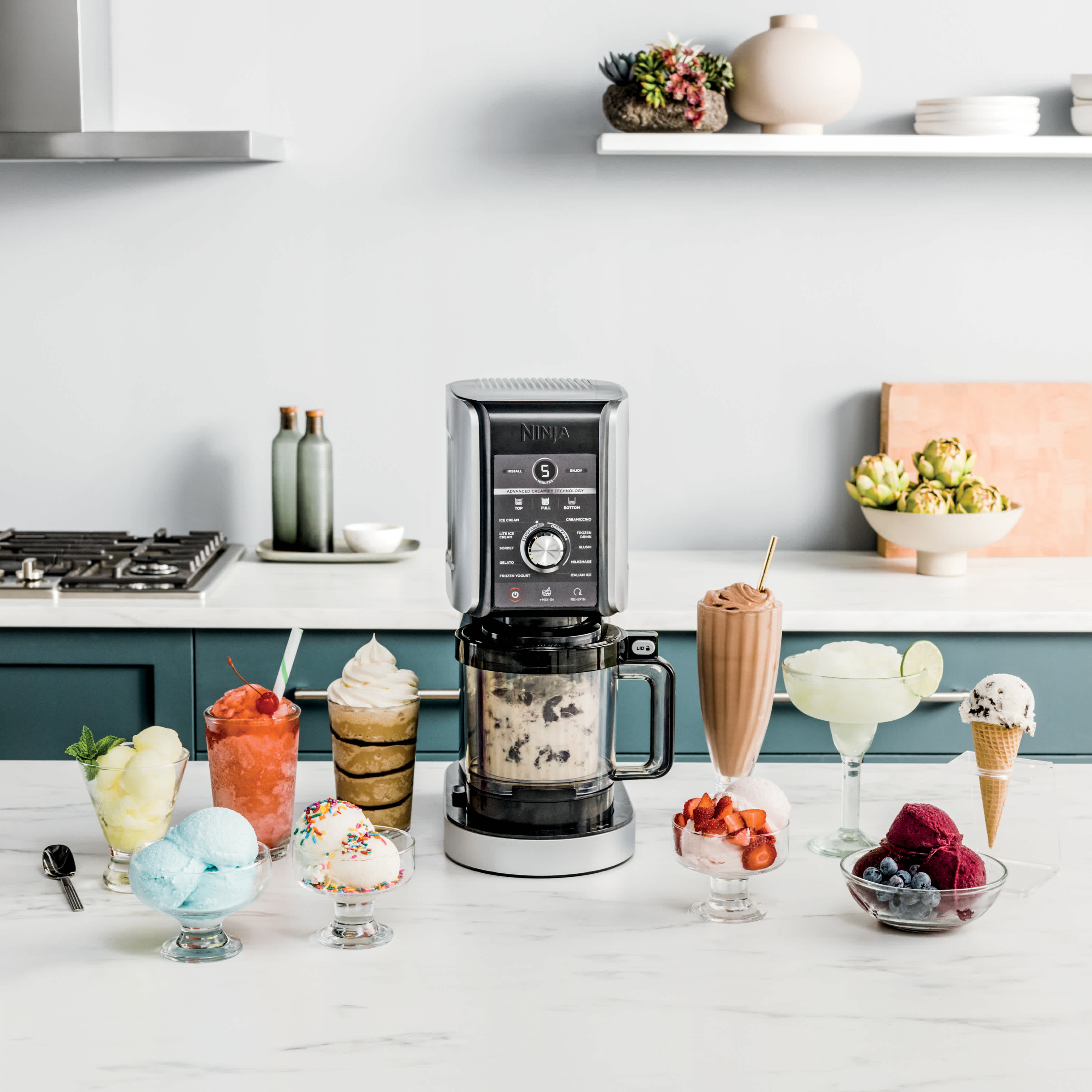 Machine &agrave; glace Ninja entour&eacute;e de desserts et de boissons pr&eacute;par&eacute;s avec l&rsquo;appareil.