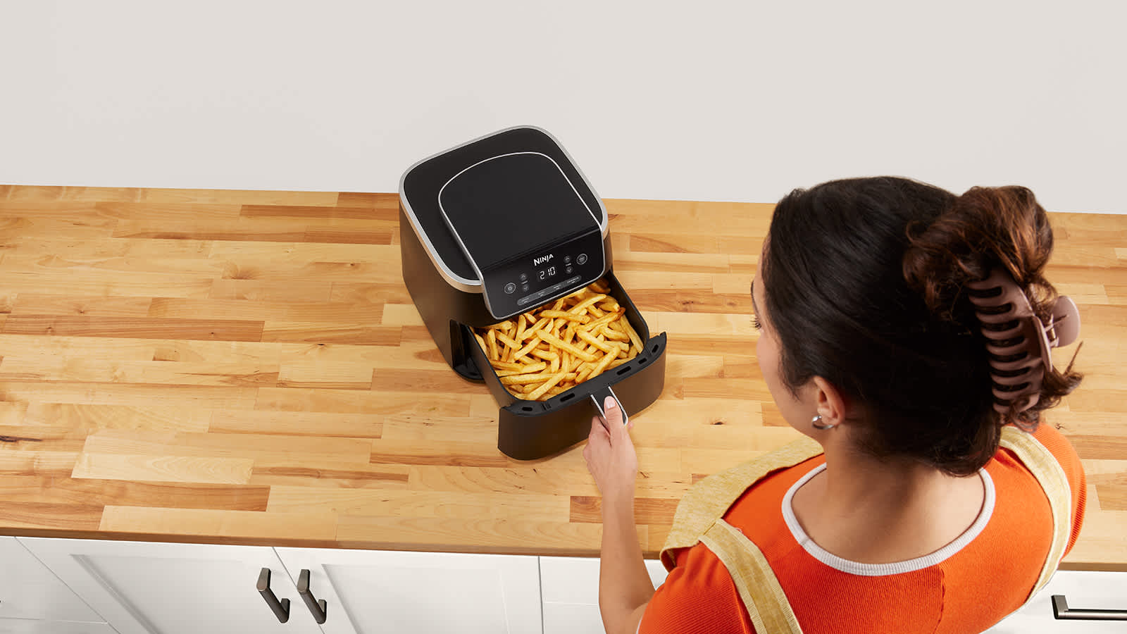 Mujer cocinando patatas fritas sin aceite en una Ninja air fryer