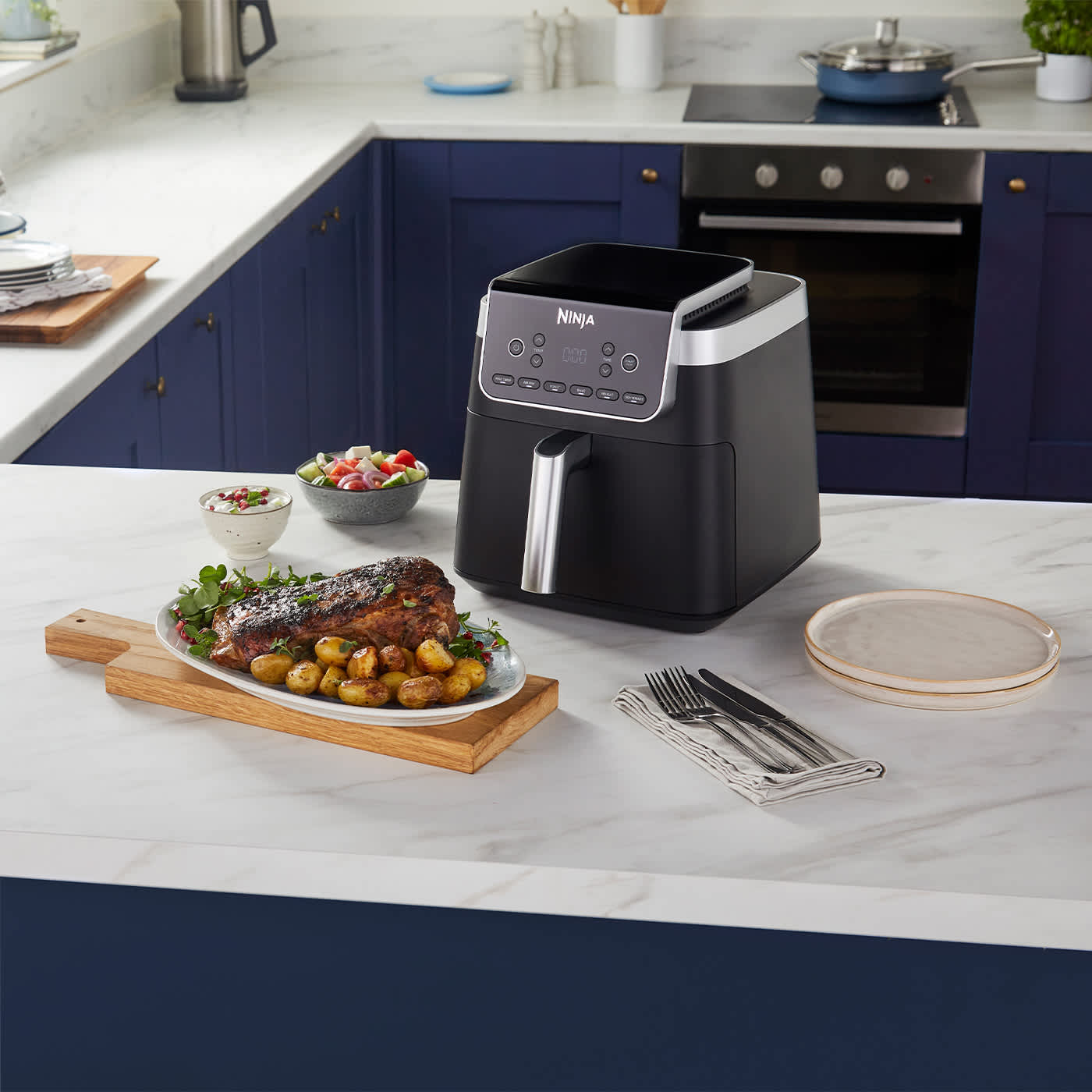 Air fryer Ninja sobre encimera rodeada  de comida