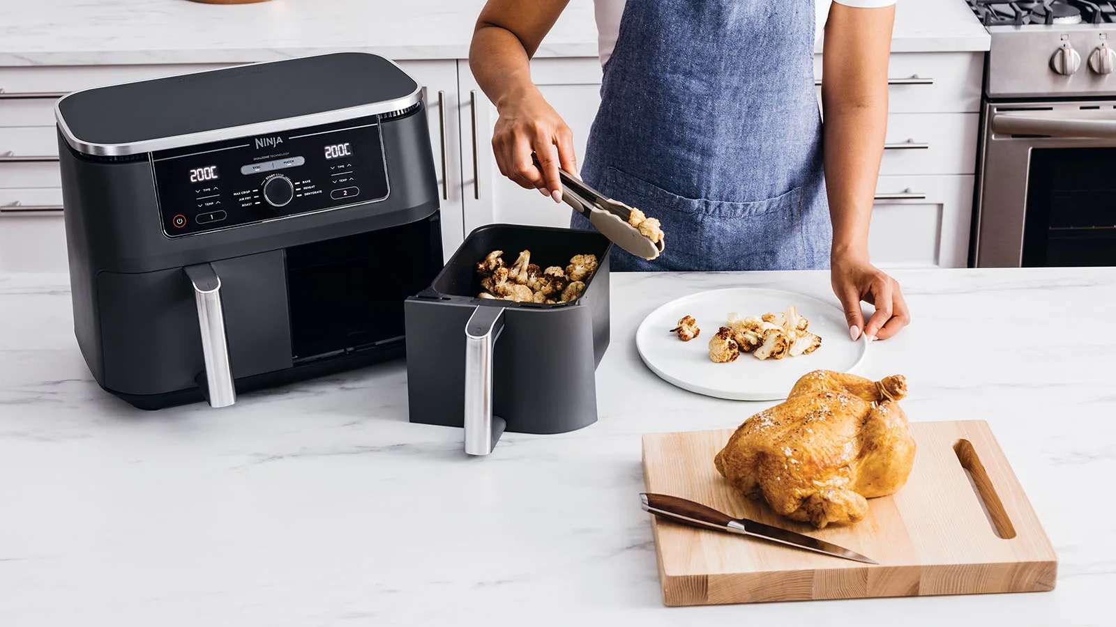 Mujer cocinando un pollo y verduras en una air fryer ninja