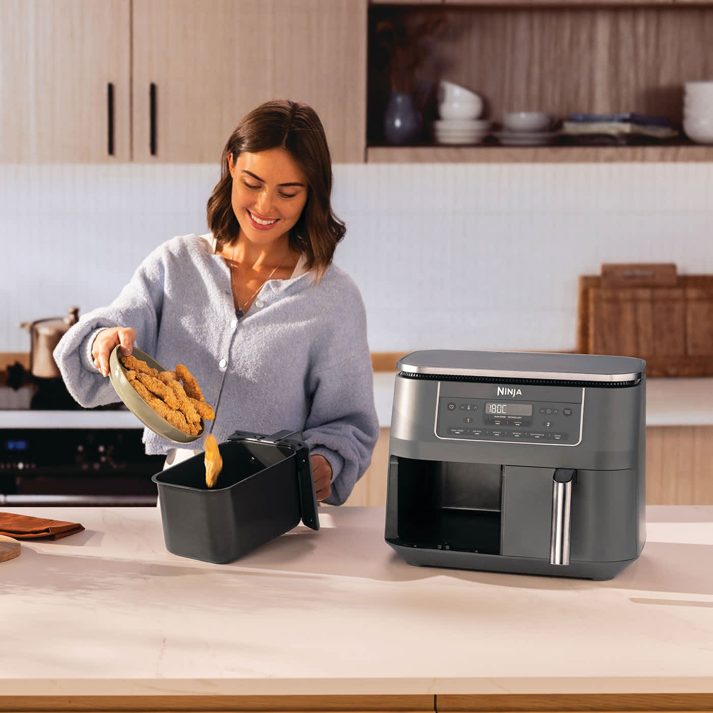 Femme versant du poulet frit dans l'air fryer.