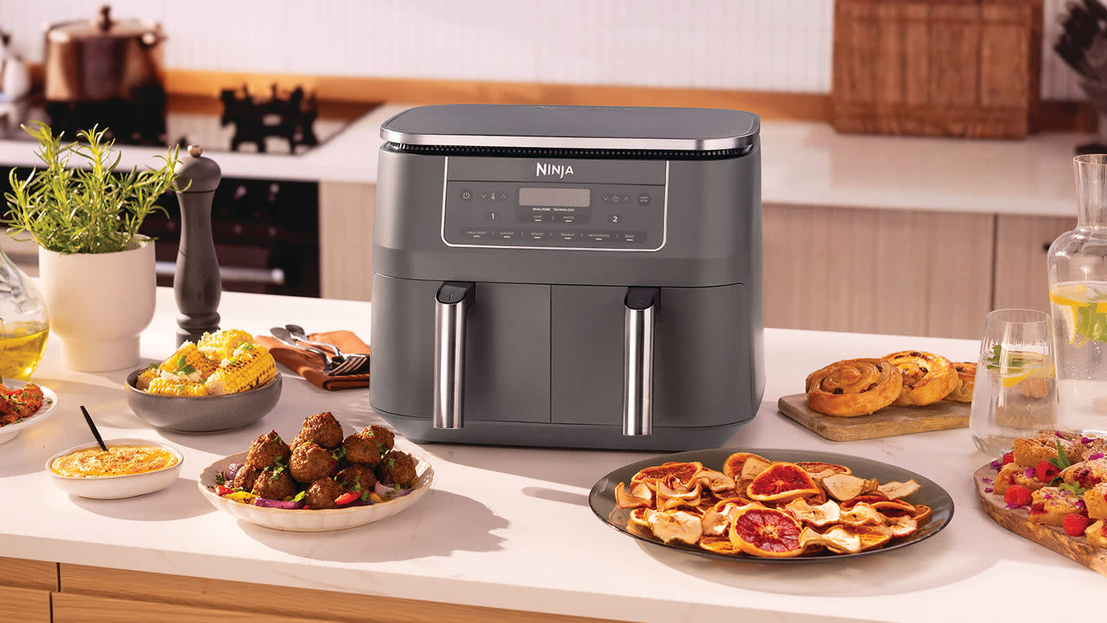 Air fryer sur une table entour&eacute; d'assiettes de nourriture.