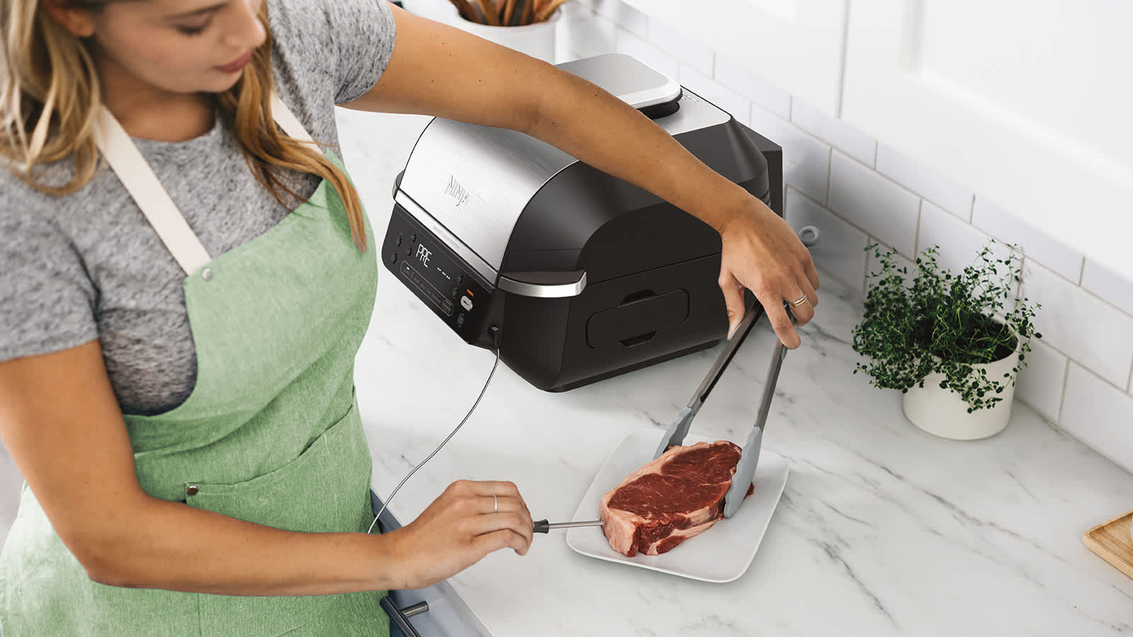 MUjer colocando el term&oacute;metro de cocci&oacute;n a un trozo de carne