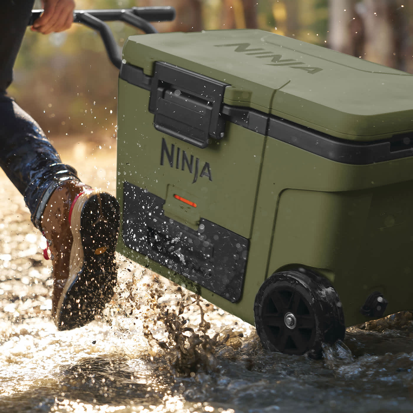Hombre transportando una neverfa ninja con ruedas por medio de un r&iacute;o