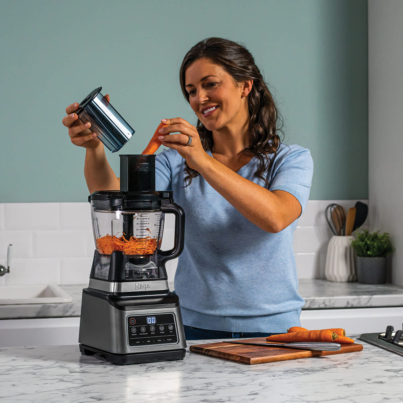 Femme r&acirc;pant des carottes avec le robot culinaire.