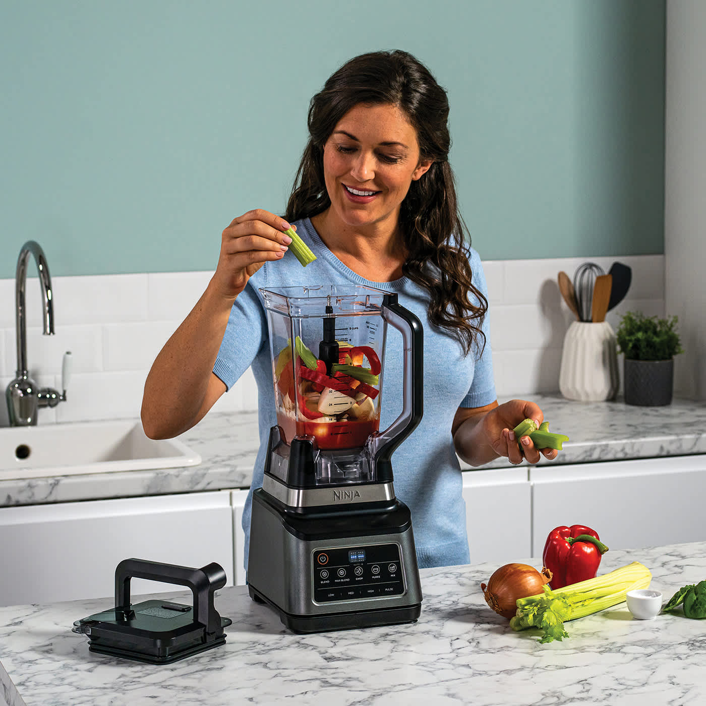 Personne ajoutant des l&eacute;gumes dans le robot culinaire.