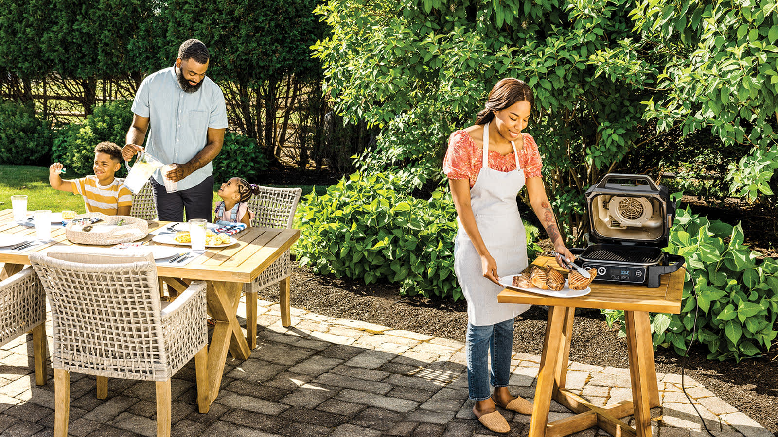 Familia en un jard&iacute;n comiendo con la barbacoa ninja
