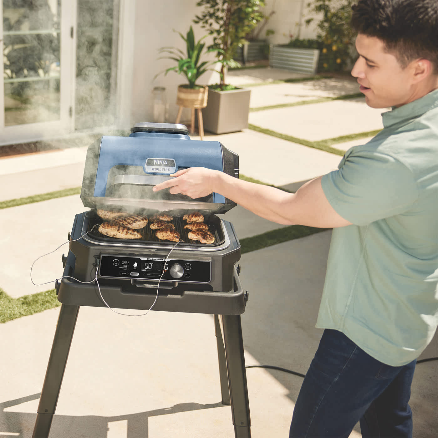 Personne cuisant de la viande sur un barbecue Ninja en utilisant la fonction thermom&egrave;tre.