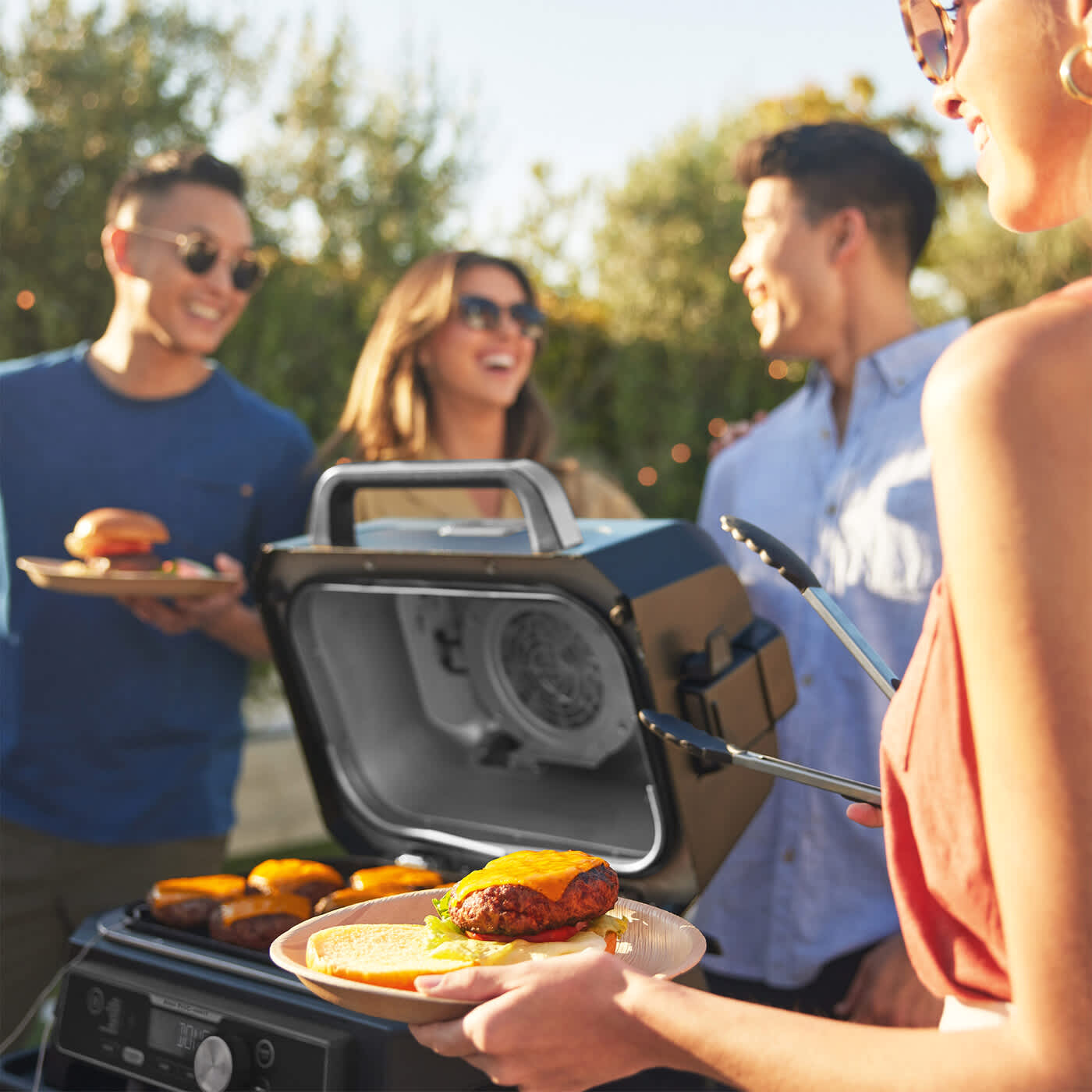 Grupo de amigos haciendo una barbacoa en un jard&iacute;n