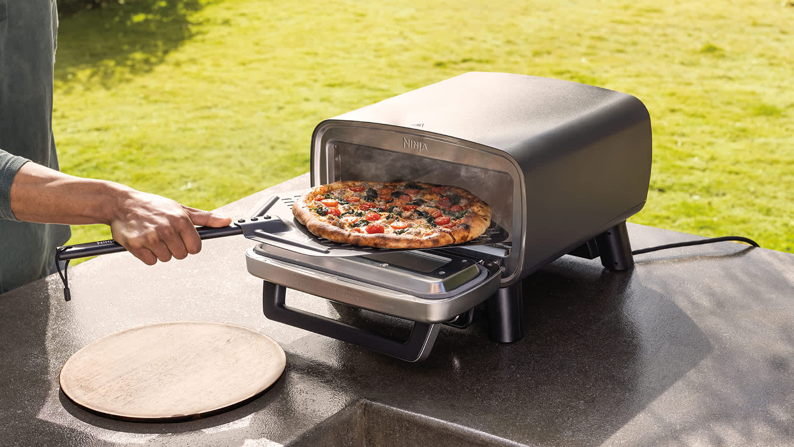 Hombre sacando una pizza del horno exterior Ninja