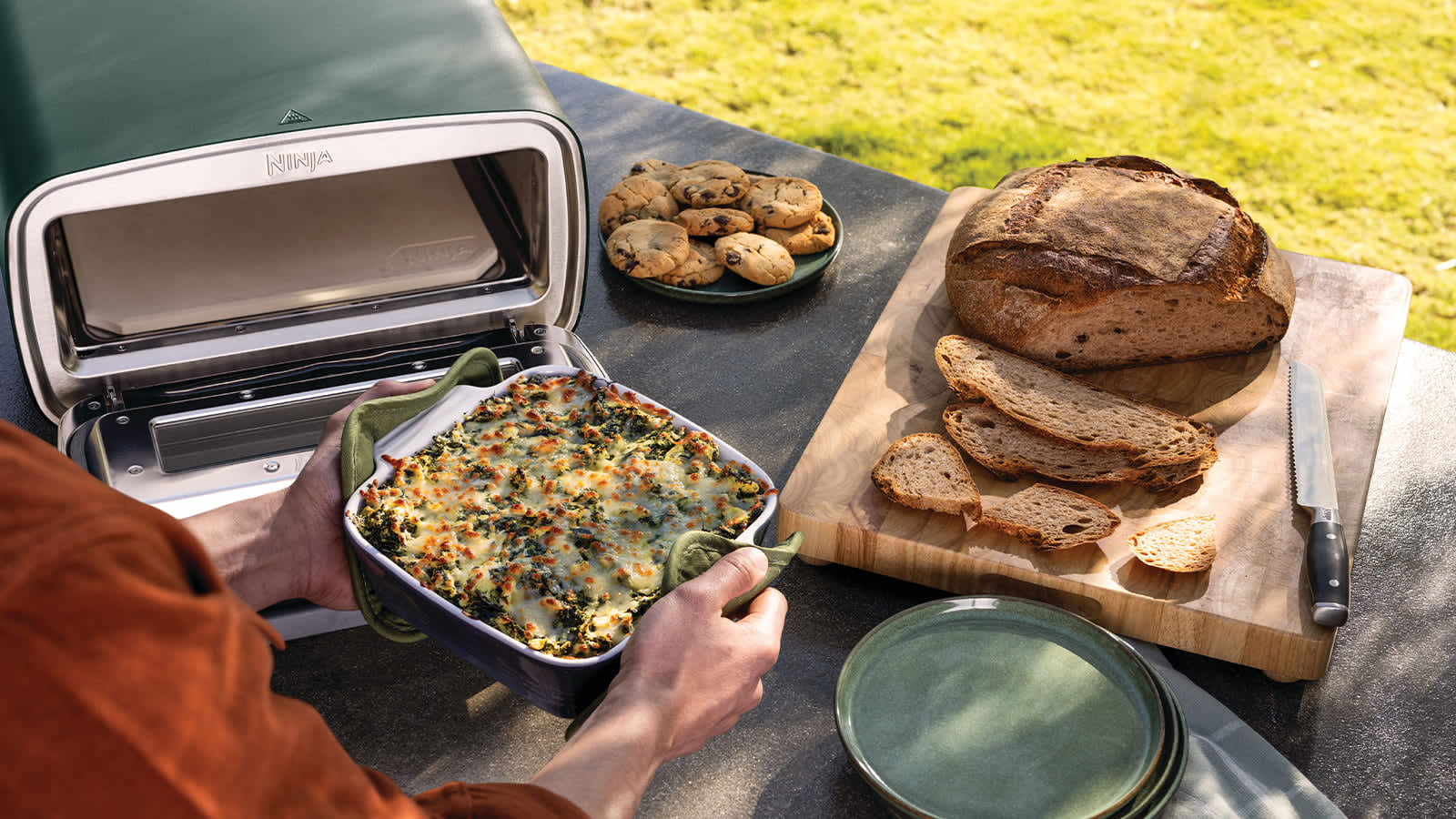 Personne cuisinant une casserole dans un four ext&eacute;rieur &eacute;lectrique Ninja.