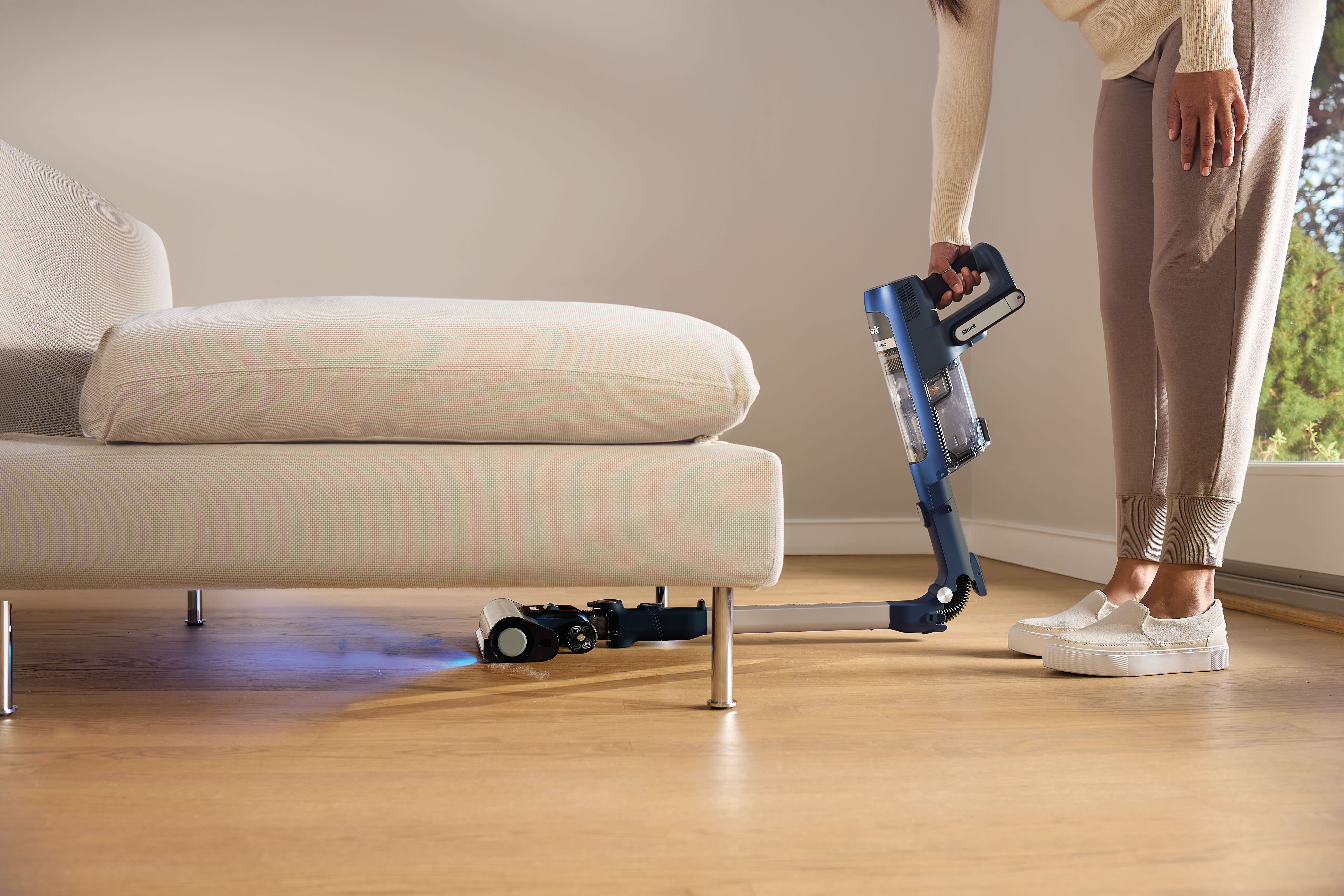 aspiradora shark doblada aspirando bajo un mueble