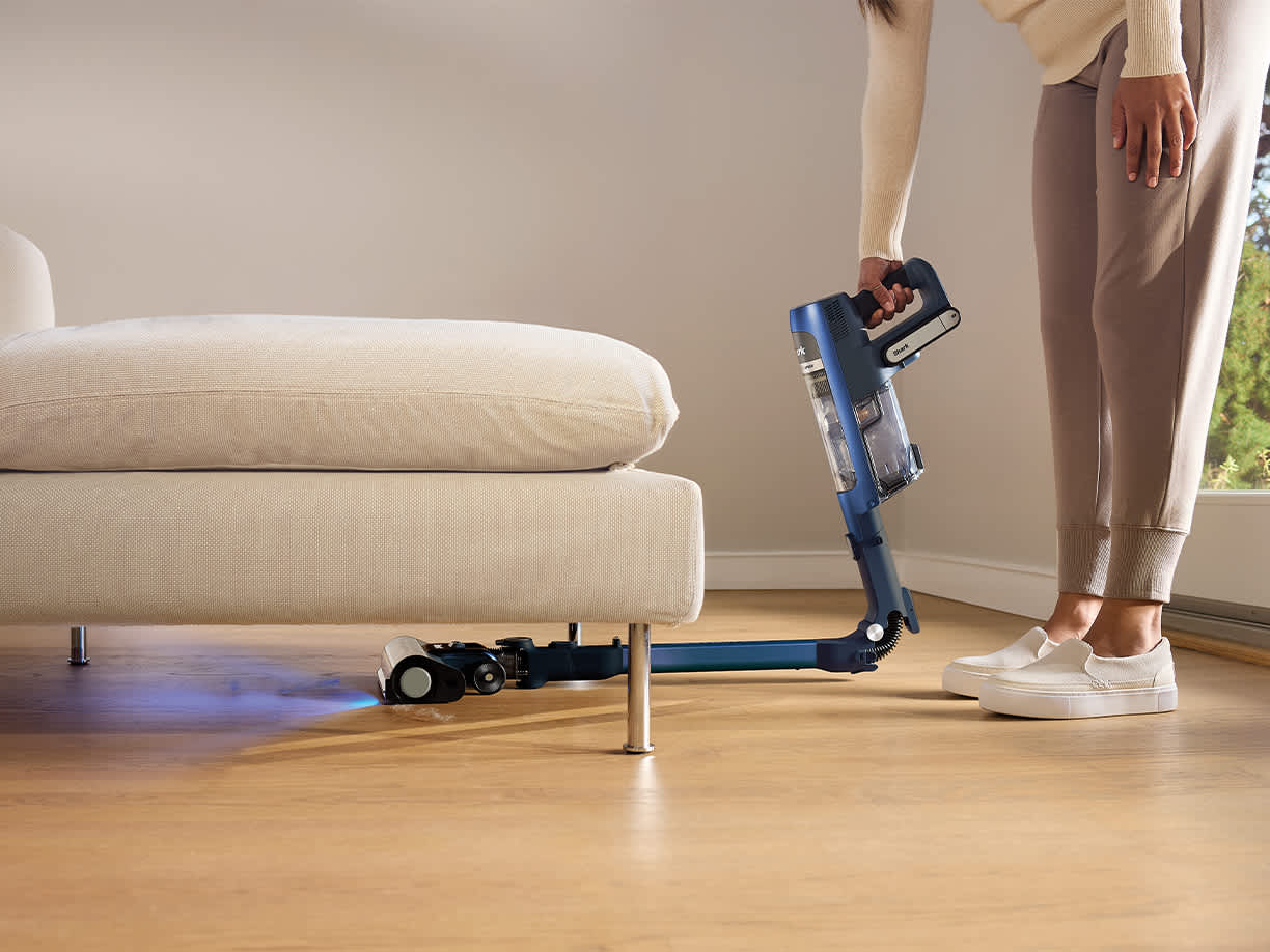 aspiradora shark con tecnolog&iacute;a flexology plegada aspirando bajo un sof&aacute;
