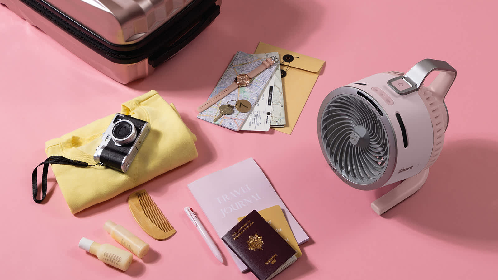 ventilador rosa rodado de varios objetos (c&aacute;mara, pasaporte)