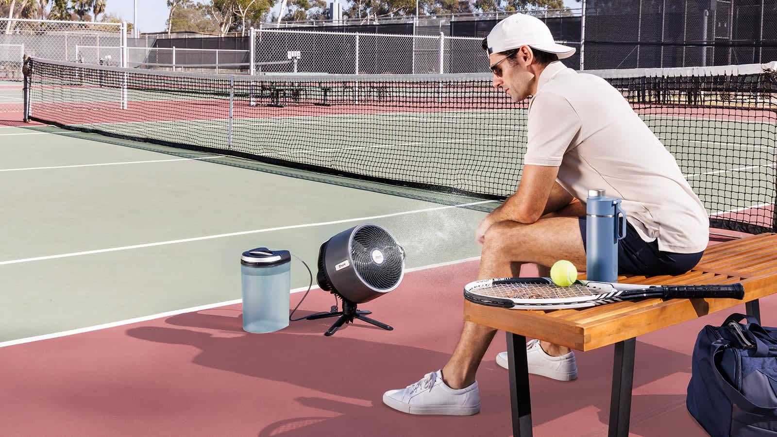 Homme utilisant un ventilateur Shark avec fonction brumisation sur un court de tennis.