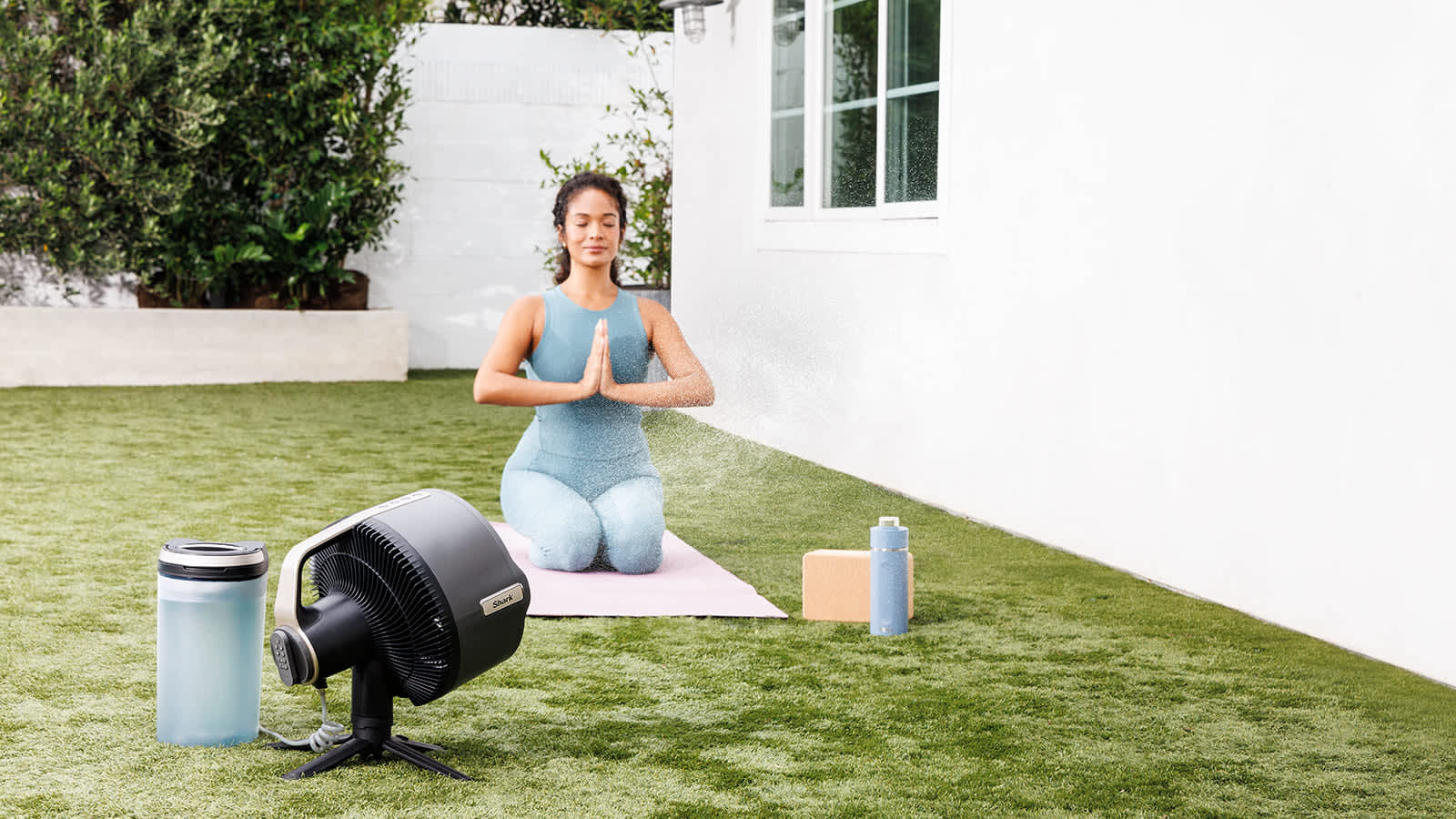 Femme faisant du yoga avec un ventilateur Shark dot&eacute; de la fonction brumisation.
