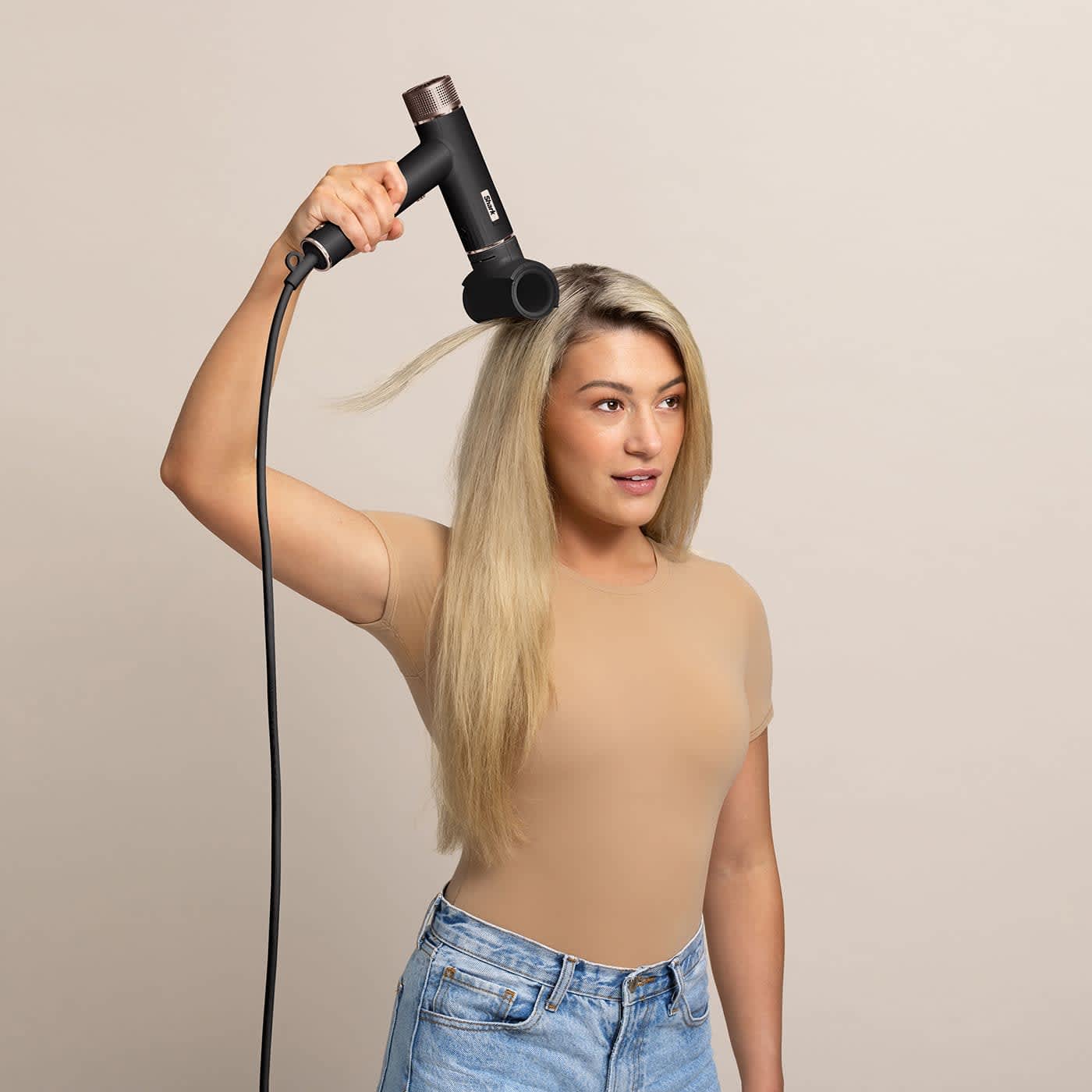 Modelka o długich blond włosach suszy je suszarką do włos&oacute;w Shark SpeedStyle Pro FLEX HD542U z końc&oacute;wką do wykańczania stylizacji FrizzFighter