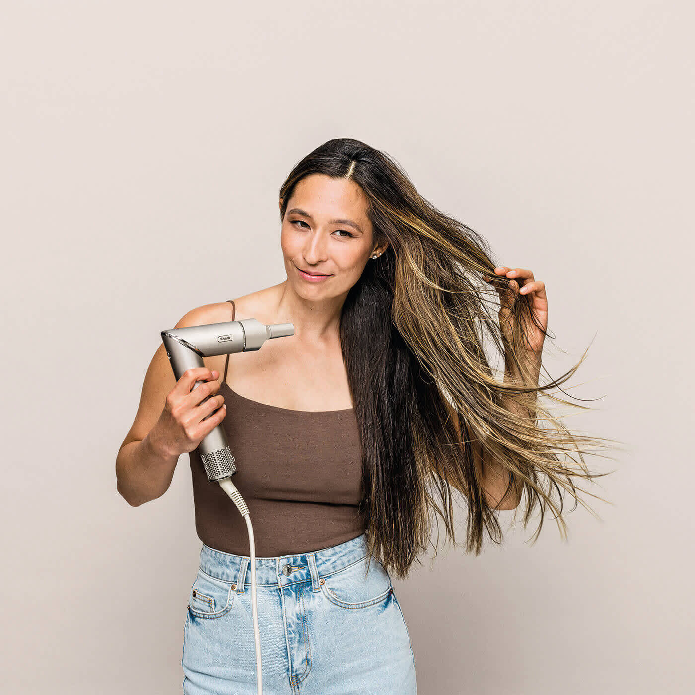 Femme se s&eacute;chant les cheveux lisses au s&egrave;che-cheveux.