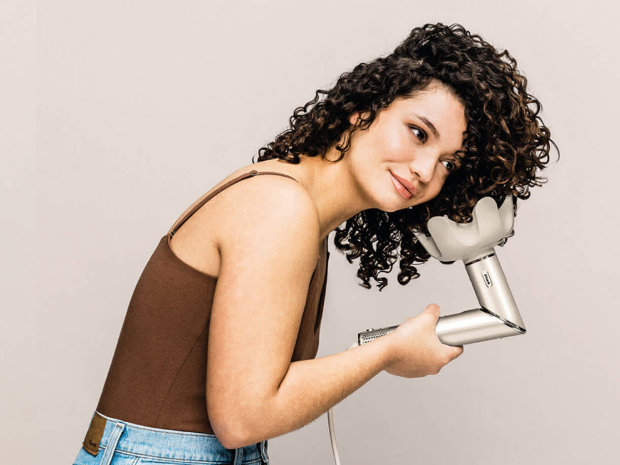 Mujer usando el difusor del moldeador de pelo shark flexstyle