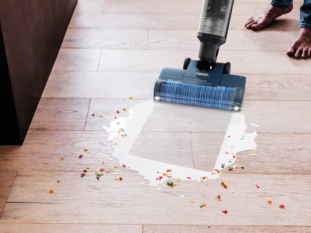Hombre aspirando y fregando a la vez leche con cereales en el suelo