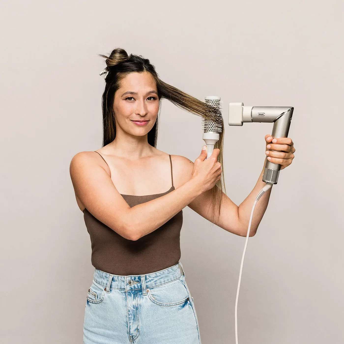 Femme se s&eacute;chant les cheveux avec une brosse et un s&egrave;che-cheveux.