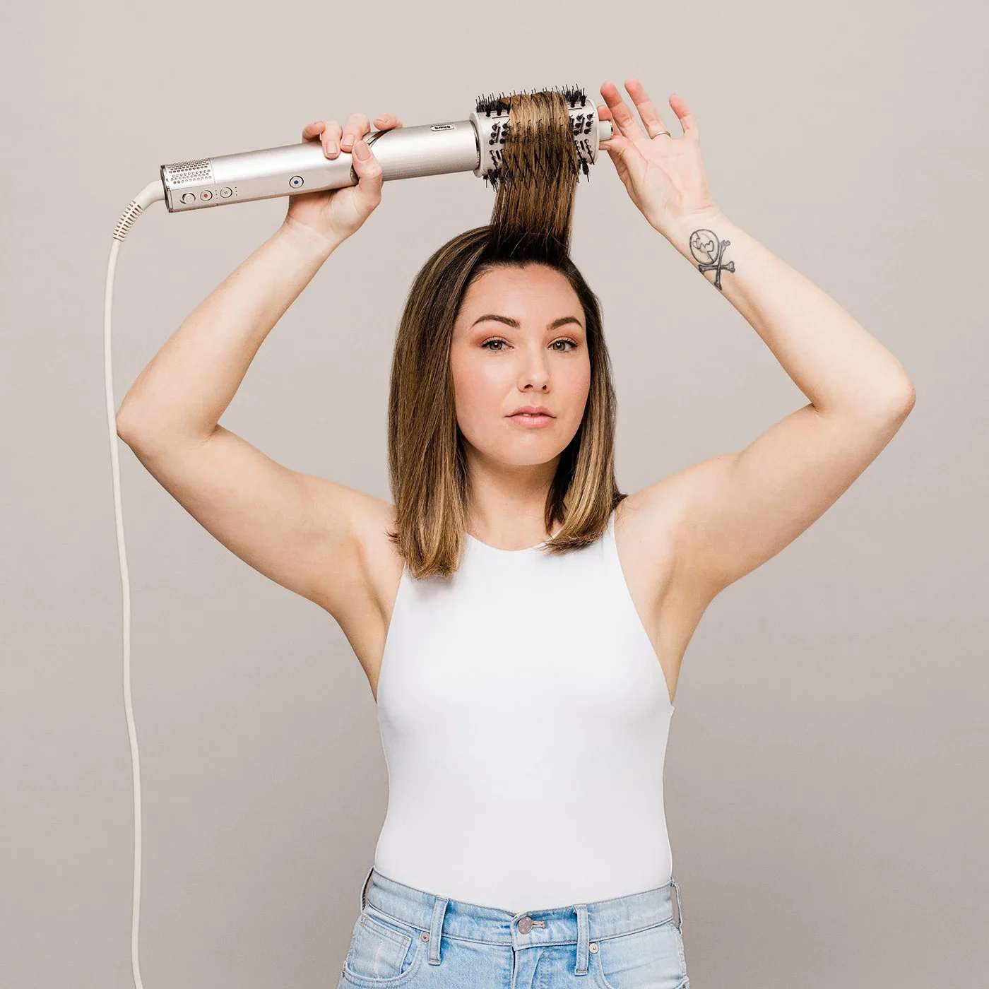 Femme se s&eacute;chant les cheveux avec une brosse ronde.