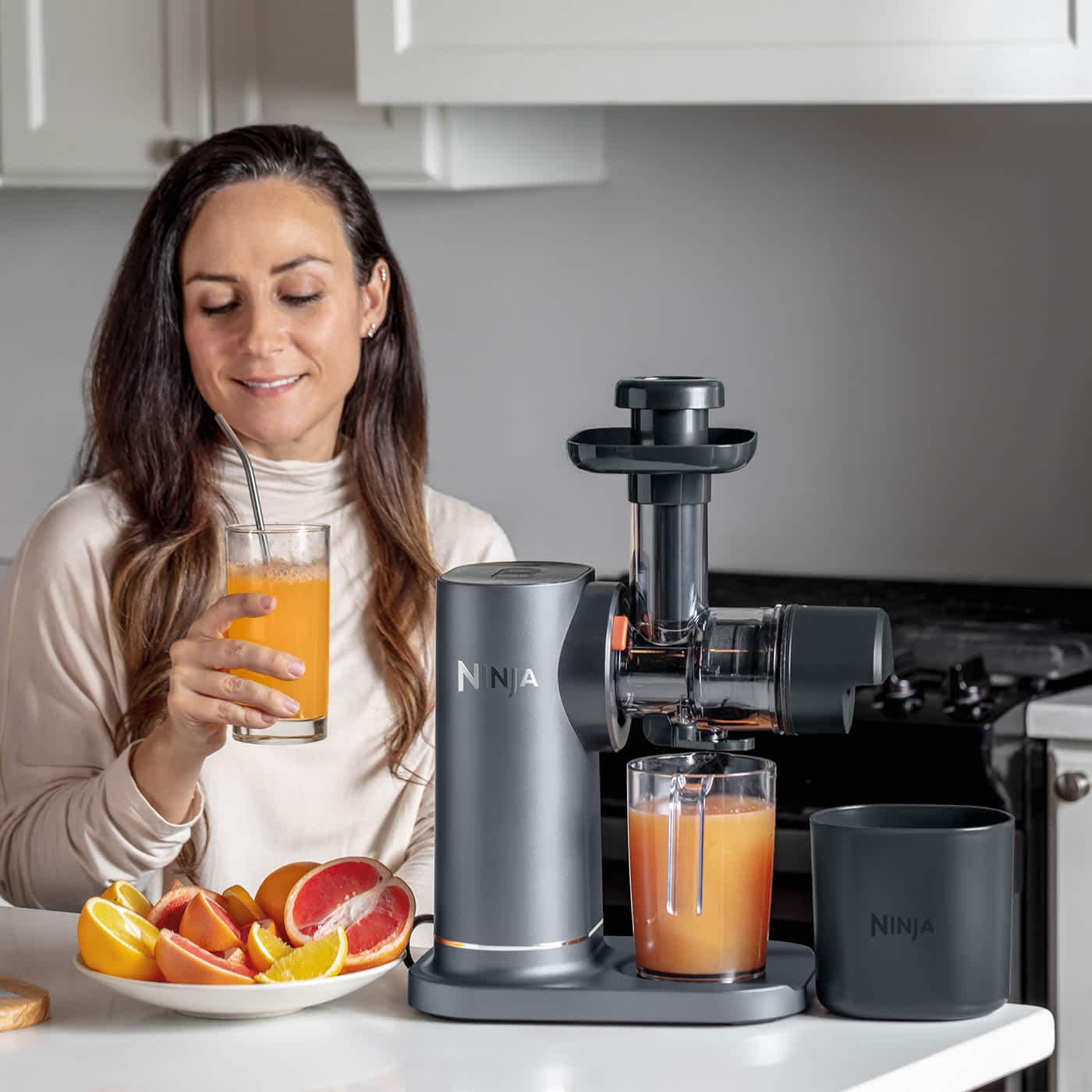 Femme buvant un jus pr&eacute;par&eacute; avec un extracteur de jus.