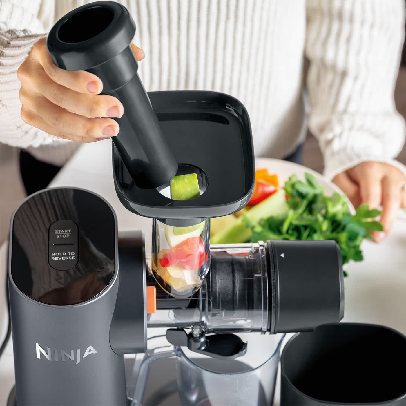 Personne ajoutant des fruits dans un extracteur de jus.
