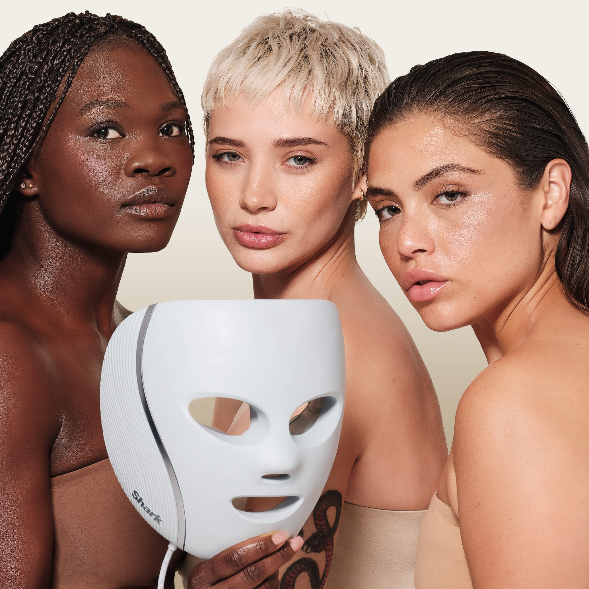 Trois femmes dont une tenant le masque LED Shark.