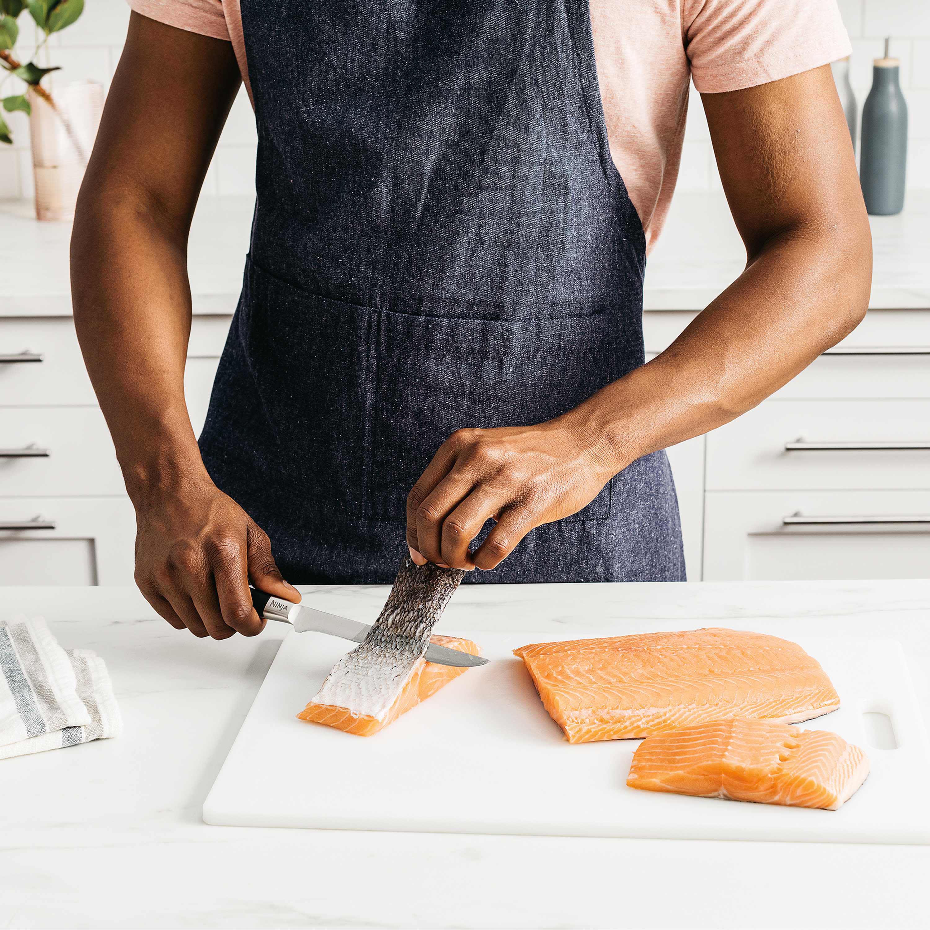 Personne retirant la peau du saumon avec un couteau.