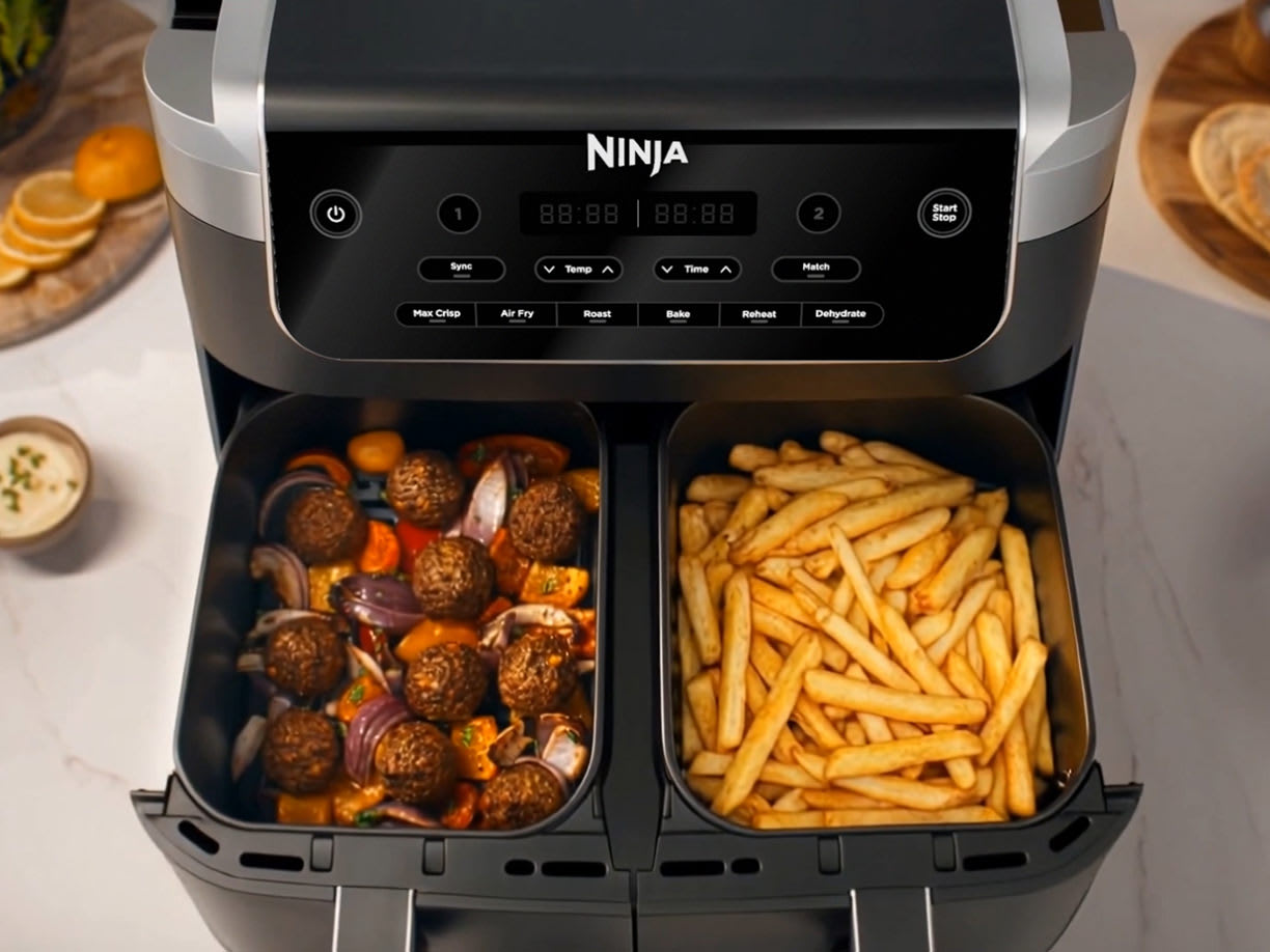 Tiroirs de l'air fryer ouverts contenant des falafels et des frites.
