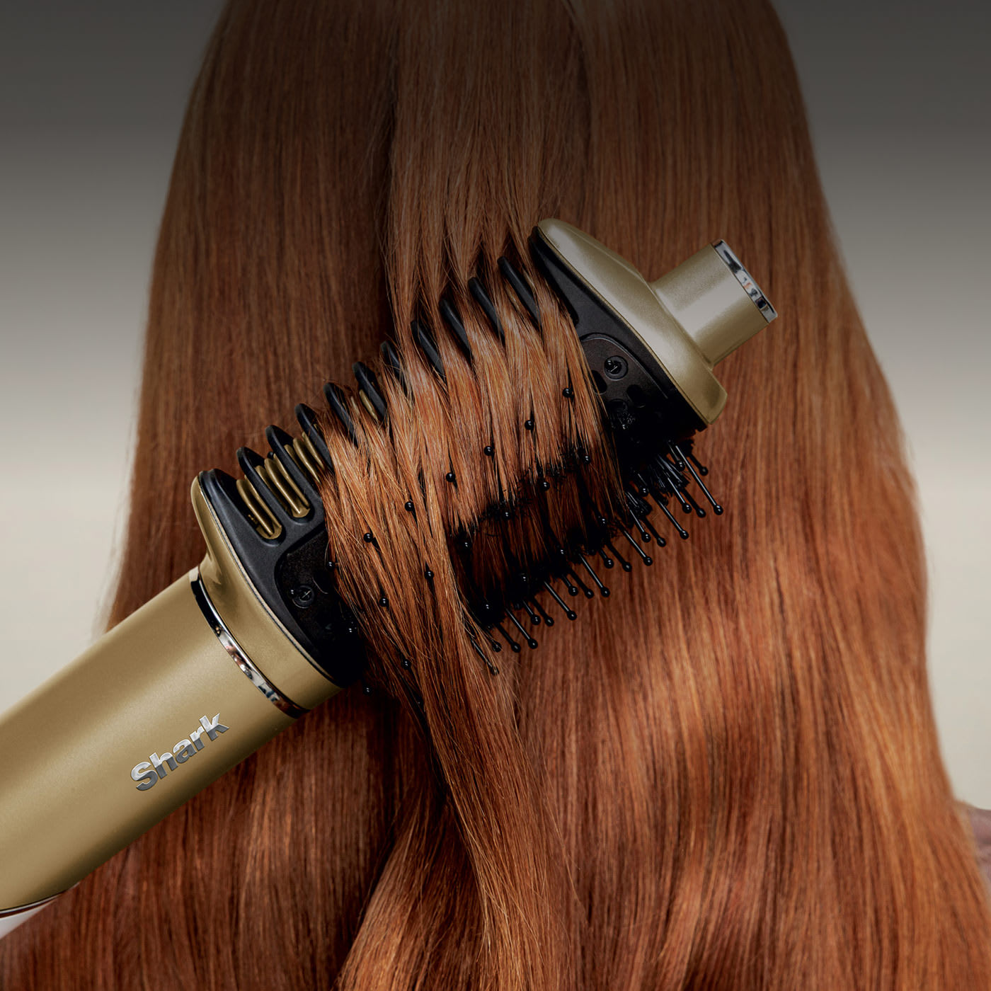 Smiling woman straightens curly hair with a gold flat iron, leaving it smooth and glossy.