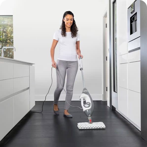 A woman cleaning the kitchen floor with a shark steam mop