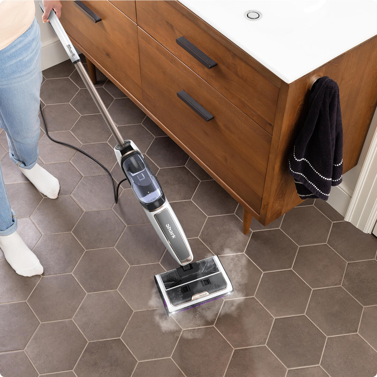 A person using the Shark SteamPickUp on a brown tiled bathroom floor